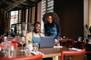 Restaurant managers working with laptop. Alberta food and beverage leaders, join PolicyWise for a free 1.5-hour virtual session for to shape welcoming workplace training. Learn how you can share your 